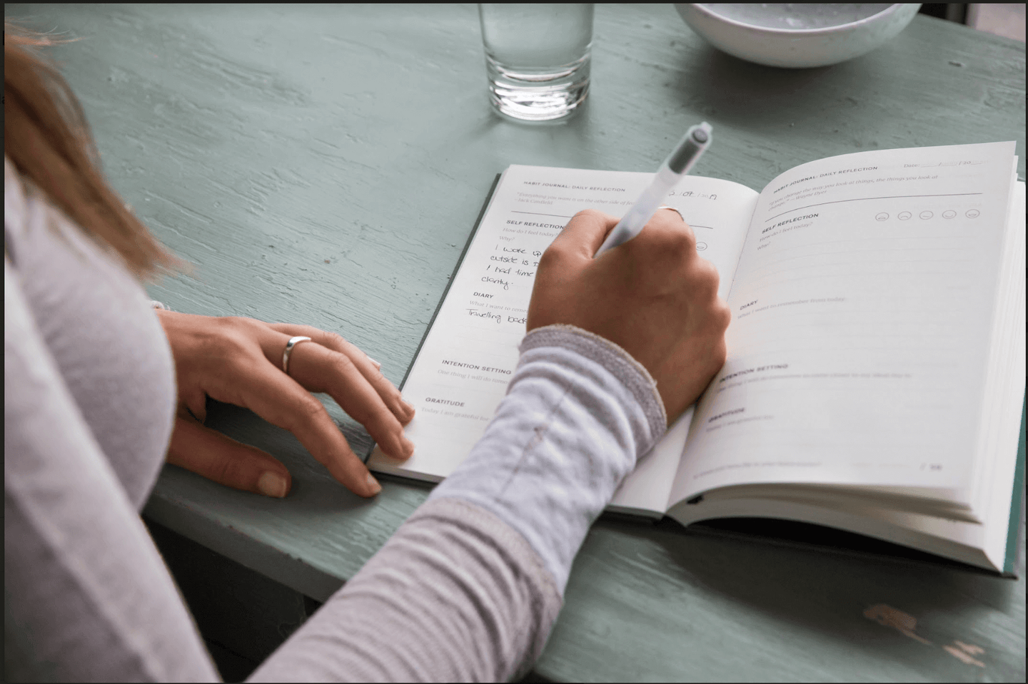 Woman writing in Evergreen Journals Habit Journal